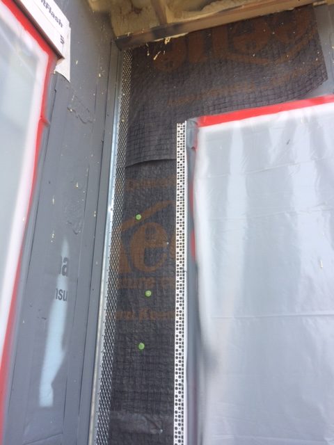 Se muestra un acercamiento del sistema de control de lluvia Driwall Rainscreen instalado con perfil metálico galvanizado a lo largo de la jamba de la puerta.