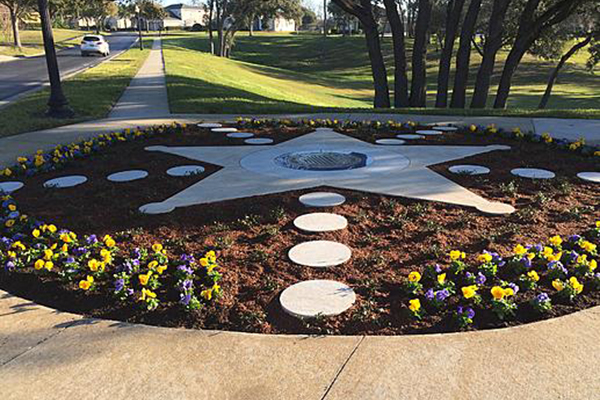 La imagen muestra un proyecto de Jimbo's Creative Masonry, un medallón de bronce que honraba a Scott Pine, oficial caído originario de Florida.